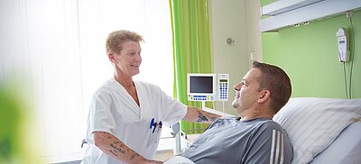 Pflegehelferin bei Patient am Pflegebett